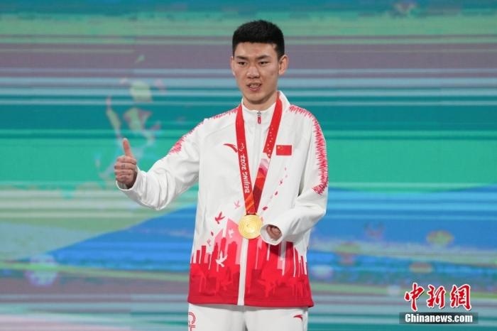 3月6日，梁景怡在延慶頒獎廣場領(lǐng)獎臺上豎起大拇指。當(dāng)日，在國家高山滑雪中心舉行的北京2022年冬殘奧會殘奧高山滑雪男子超級大回轉(zhuǎn)—站姿決賽中，中國選手梁景怡奪得冠軍。 <a target='_blank' href='/'>中新社</a>記者 楊華峰 攝