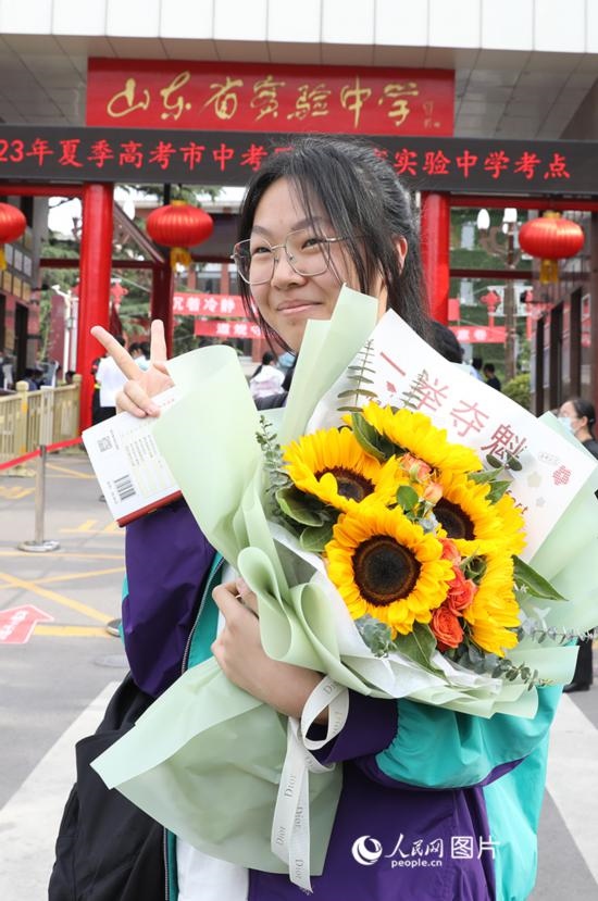 6月7日高考首日，山東67萬考生走進考場，拼搏逐夢。在山東省實驗中學考點，考生進考場前手捧向日葵花拍照留念，寓意“一舉奪魁”。人民網(wǎng)記者 劉祺攝