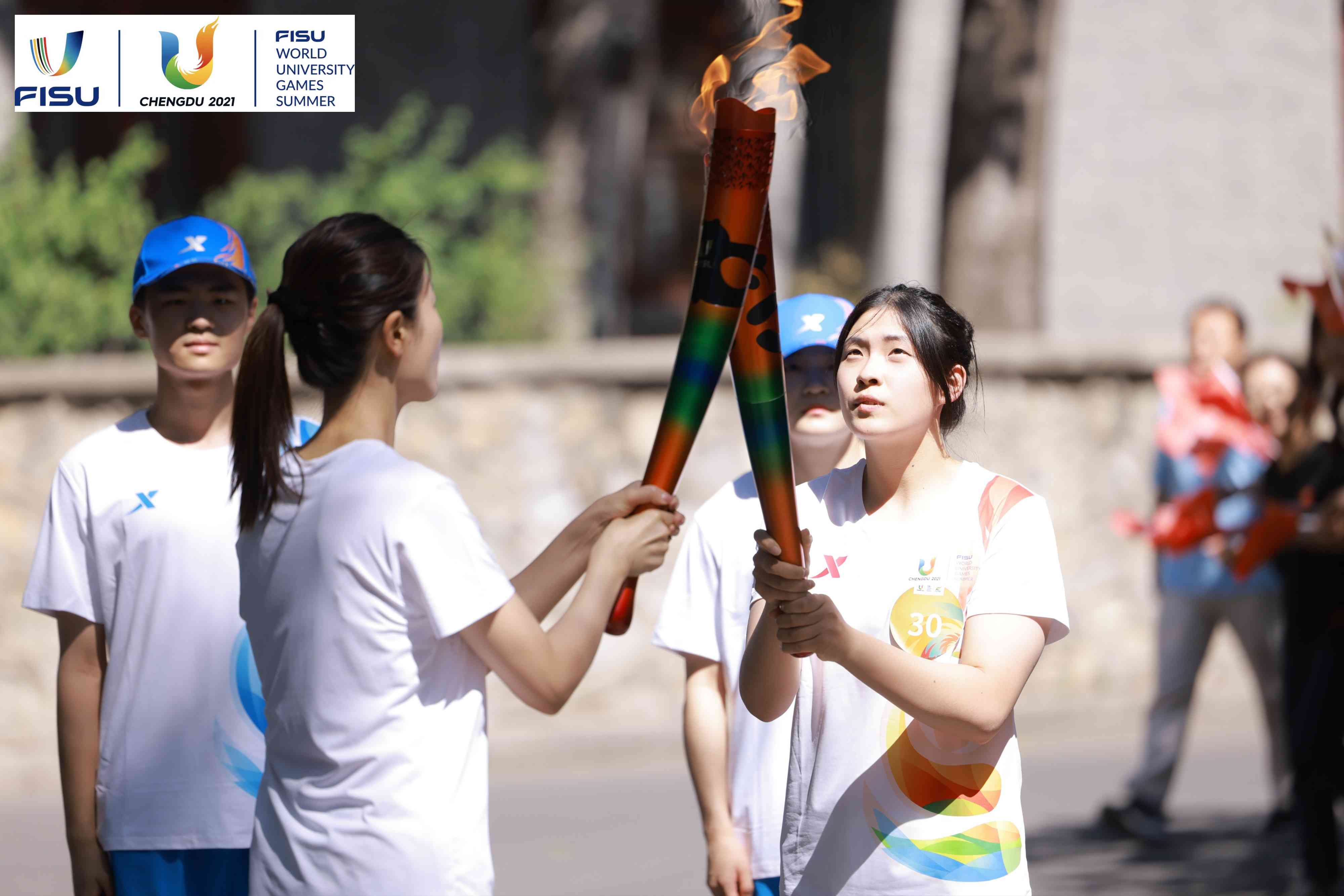 兩名大運(yùn)會火炬手進(jìn)行火炬?zhèn)鬟f。 圖片來源：成都大運(yùn)會執(zhí)委會供圖