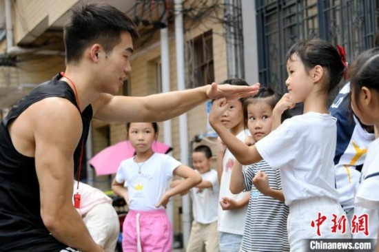 圖為大學(xué)生志愿者在組織孩子們參加體育健身活動。廖光福 攝