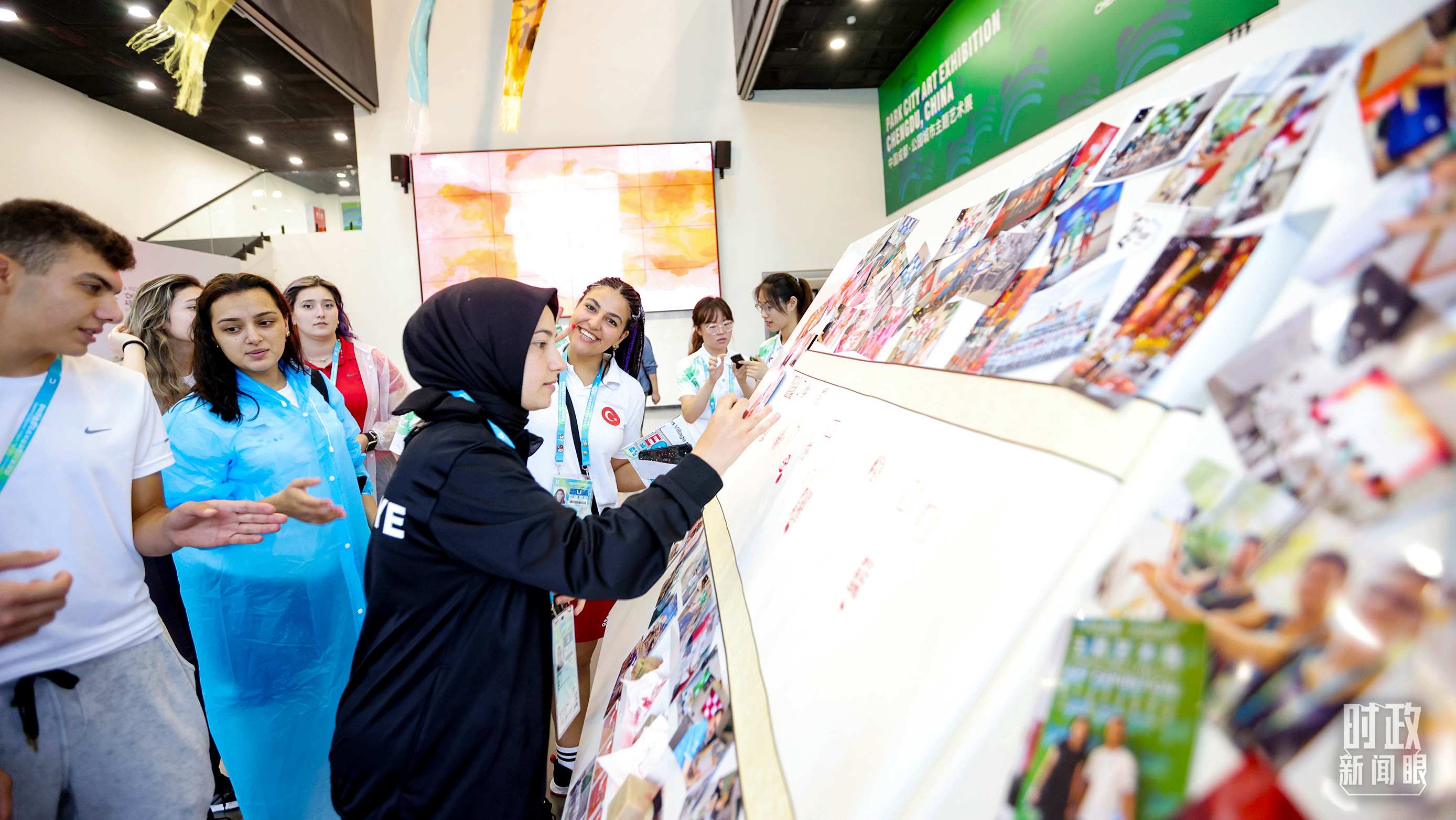 各國青年運(yùn)動員正在參觀成都大運(yùn)村內(nèi)的“雪山下的公園城市，煙火里的幸福成都”主題藝術(shù)展。（總臺央視記者魏幫軍拍攝）