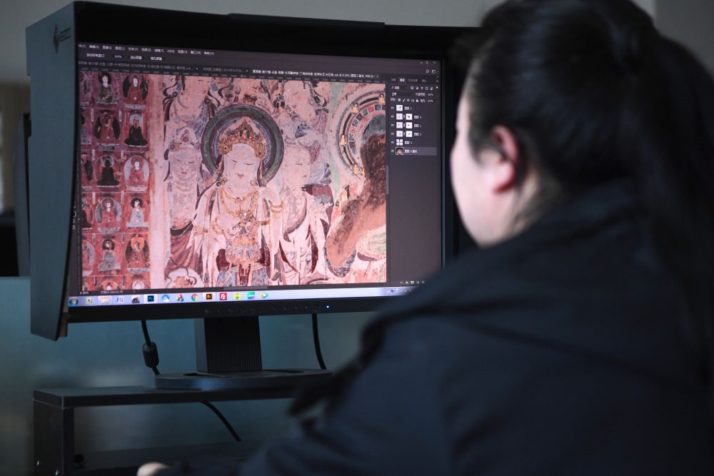 敦煌研究院文物數(shù)字化保護團隊圖像處理人員年海麗在拼接壁畫圖像（2023年4月25日攝）。數(shù)字化探索為莫高窟的保護與傳承開辟了全新路徑，數(shù)字技術(shù)讓敦煌文物走出洞窟，跨出國門，走向“永久保存、永續(xù)利用”。新華社記者 陳斌 攝