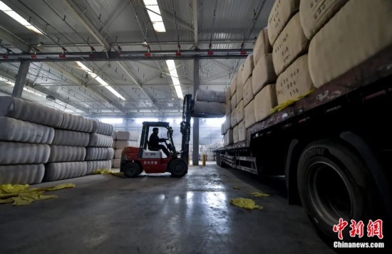 新疆喀什綜合保稅區(qū)，喀什啟路國際貿(mào)易有限公司的倉庫內(nèi)，工人正在裝載從塔吉克斯坦和烏茲別克斯坦進口的棉花。劉新攝