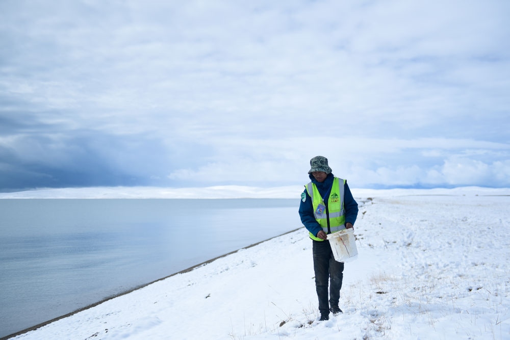 2021年10月20日，在青海省果洛藏族自治州瑪多縣扎陵湖鄉(xiāng)勒那村，三江源國家公園黃河源園區(qū)生態(tài)管護(hù)員在扎陵湖邊撿拾垃圾。新華社記者 張龍 攝