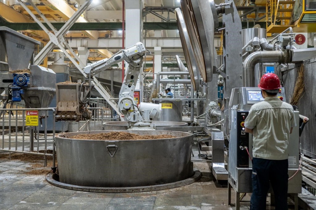 907車間里，機械臂正在撒料裝甑。嚴磊攝