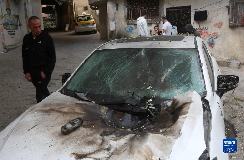 12月17日，在約旦河西岸城市圖勒凱爾姆附近的一處難民營，人們查看在沖突中損毀的車輛。新華社發(fā)（尼達(dá)爾·艾仕塔耶?dāng)z）