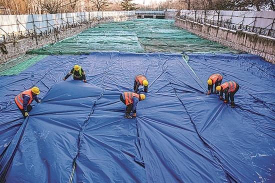 1月3日，房山區(qū)東風(fēng)街道，工人正在修復(fù)的河道內(nèi)給混凝土鋪設(shè)保溫布。