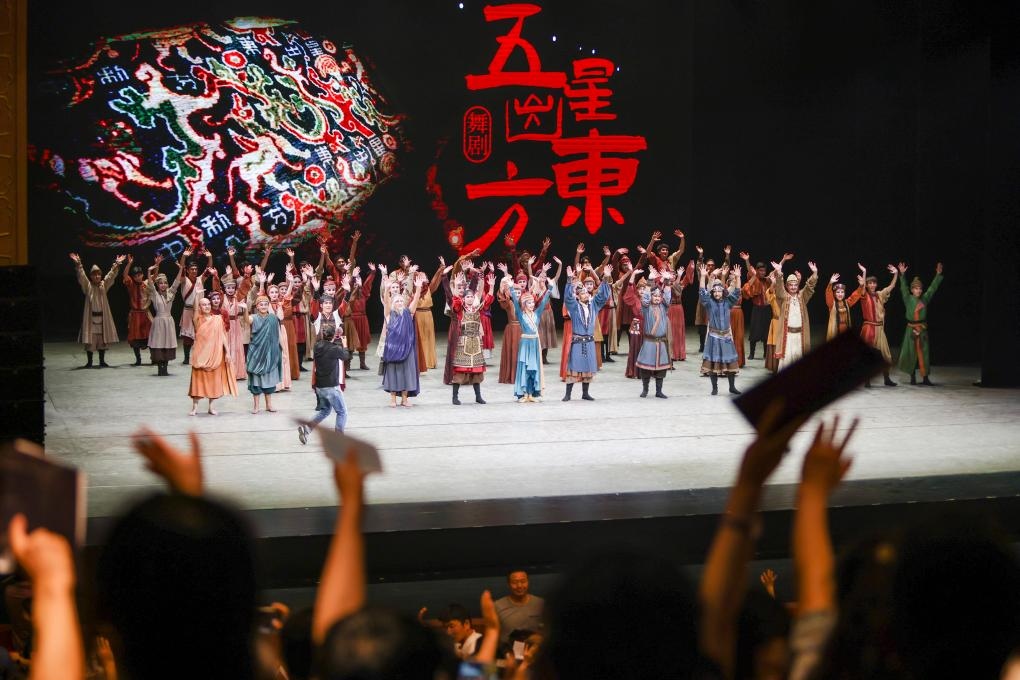 2023年7月31日，新疆和田地區(qū)新玉歌舞團(tuán)在烏魯木齊京劇院演出舞劇《五星出東方》后和觀眾互相揮手致意。這場(chǎng)演出是第六屆中國(guó)新疆國(guó)際民族舞蹈節(jié)的參演劇目之一，曾榮獲國(guó)家“文華獎(jiǎng)”等。新華社記者 郝昭 攝