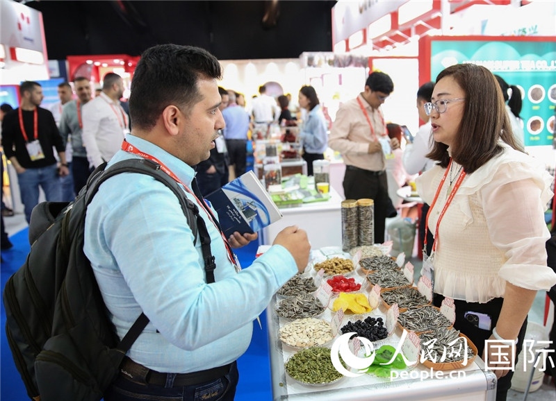 圖為一家中國干果參展企業(yè)代表與采購商洽談。人民網(wǎng) 塔里克·易卜拉欣攝
