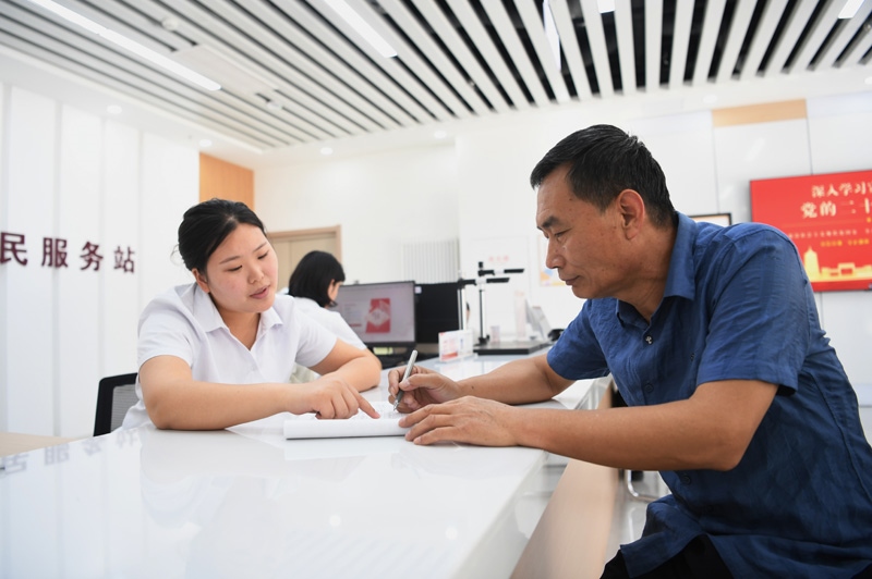 2023年5月23日，河北雄安新區(qū)容東片區(qū)南文營(yíng)社區(qū)居民（右）在社區(qū)便民服務(wù)站辦理業(yè)務(wù)。