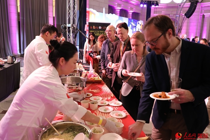 當(dāng)?shù)貢r(shí)間3月7日晚，華盛頓聯(lián)合車站廣場(chǎng)舉行駐美使團(tuán)“使館主廚挑戰(zhàn)賽”。圖為當(dāng)?shù)孛癖娫谥袊古_(tái)前體驗(yàn)中國美食。人民網(wǎng)記者 李志偉攝