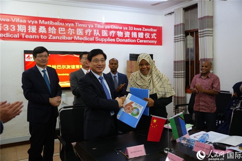 江蘇省蘇北人民醫(yī)院黨委書(shū)記束余聲與桑衛(wèi)生部首席秘書(shū)哈比巴交換捐贈(zèng)書(shū)。中國(guó)援桑醫(yī)療隊(duì)供圖