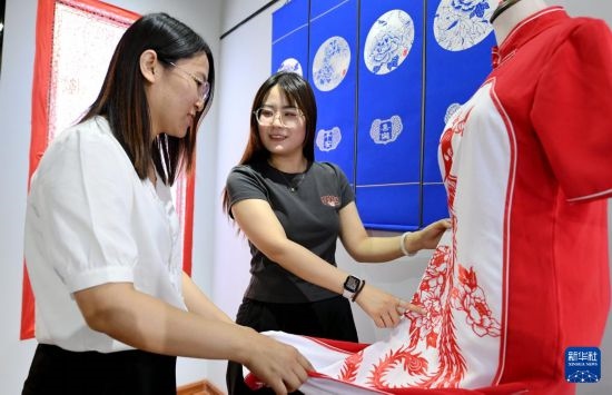 5月31日，在衡水市阜城縣一家剪紙工作室，游客在觀賞帶有剪紙?jiān)氐钠炫邸? width=