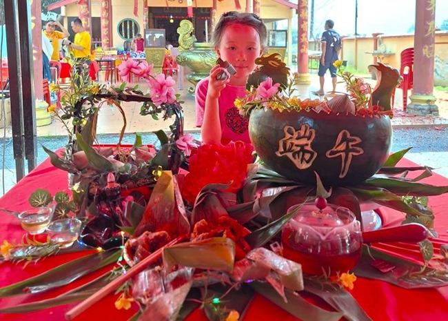 小朋友展示學(xué)裹粽子的成品照。組委會供圖