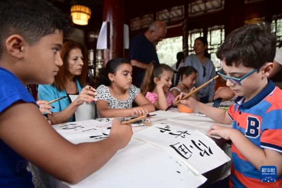7月4日，在馬耳他桑塔露琪亞市的中國(guó)古典園林“靜園”，人們體驗(yàn)中國(guó)書(shū)法。新華社發(fā)（喬納森·博格 攝）
