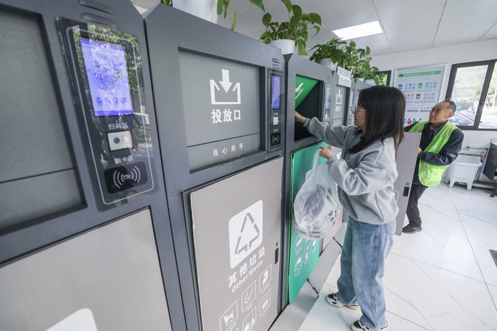 2024年4月10日，在浙江省湖州市吳興區(qū)飛英街道新華府小區(qū)內(nèi)，居民在垃圾分類智能系統(tǒng)的指導下進行垃圾分類投放，居民的投放情況將實時匯總到智慧服務平臺，會有相應的積分獎勵。新華社記者 徐昱 攝