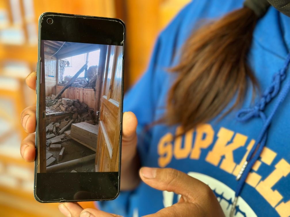 圖為7月17日拉毛東智在手機(jī)上找出地震后房屋受損的照片。新華社記者 張子琪 攝