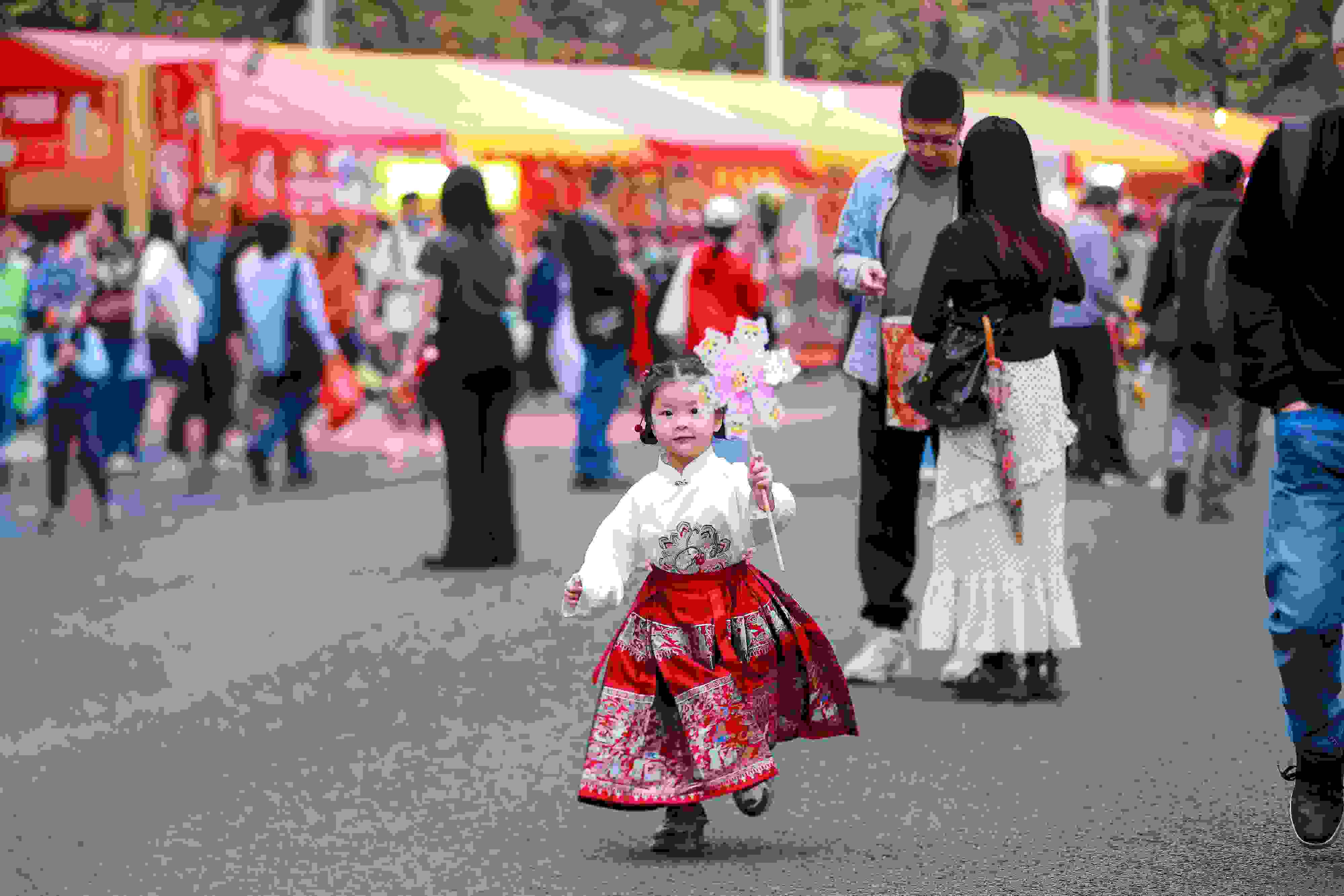 拿著風(fēng)車穿著馬面裙的小女孩在廣州的花市上開心奔跑。