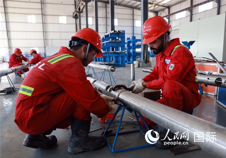 中伊員工共同在檢修鉆井設(shè)備。人民網(wǎng)記者管克江攝