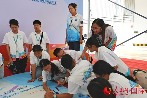 泰國學生在開營儀式展板上繪制圖案。人民網(wǎng)記者 白元琪攝