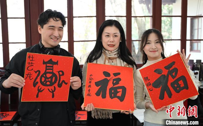 1月20日，外籍留學生和西泠印社社員李硯(中)展示各自創(chuàng)作的福貼。當日，來自巴西、馬來西亞、加納、哈薩克斯坦的外籍留學生在浙江杭州西泠印社體驗福貼、春聯(lián)和篆刻，感受古老的中國傳統(tǒng)文化。中新社記者 王剛 攝