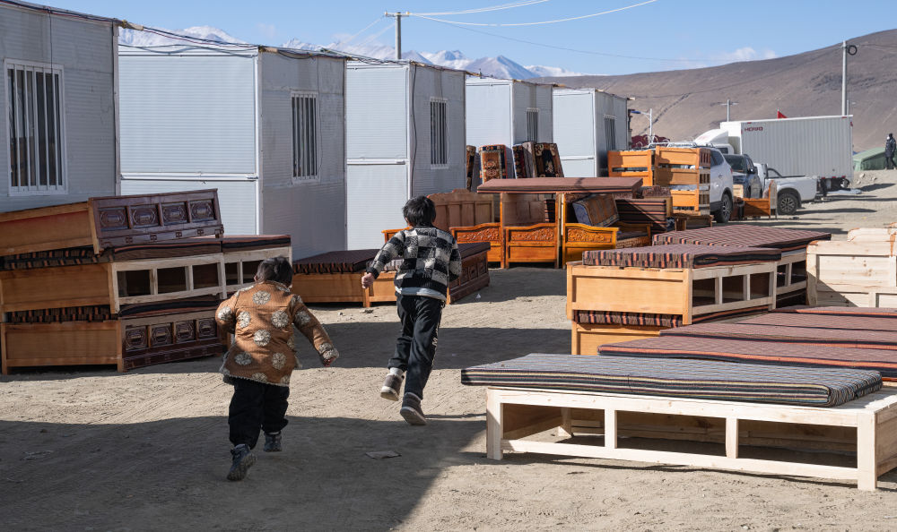 2025年1月13日，在定日縣嘎旦村，兩個(gè)孩子在剛運(yùn)來的兩排藏床間奔跑。新華社記者丁增尼達(dá) 攝