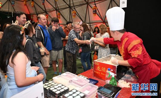 圖為游客在燈節(jié)現(xiàn)場購買小吃。（圖片由奧克蘭中國文化中心提供）