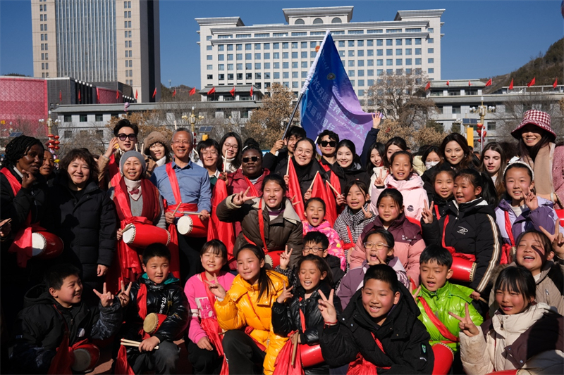 中外青年學(xué)子在安塞文化廣場觀看陜北腰鼓和大秧歌表演后合影留念，大家踏著鼓點共舞，翻飛的紅綢與躍動的身影交織，在黃土地廣場上繪出一幅生動的陜北民俗互動畫卷