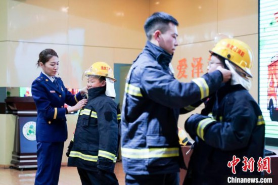 圖為學生們現(xiàn)場穿戴消防頭盔和戰(zhàn)斗服。中新社記者 趙宇航 攝