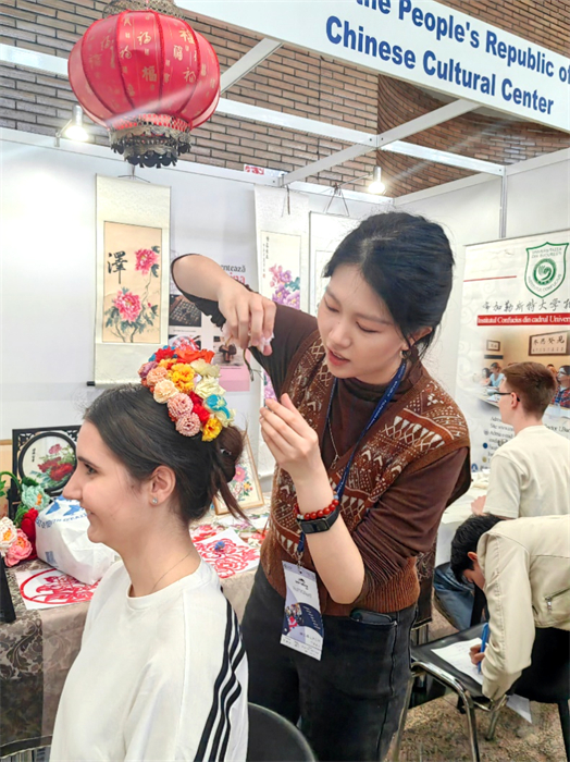 展覽正值羅馬尼亞迎春花節(jié)，國際中文教師志愿者潘婧穎向游客們介紹了國家非物質(zhì)文化遺產(chǎn)——福建泉州的簪花文化。布加勒斯特大學孔子學院供圖。