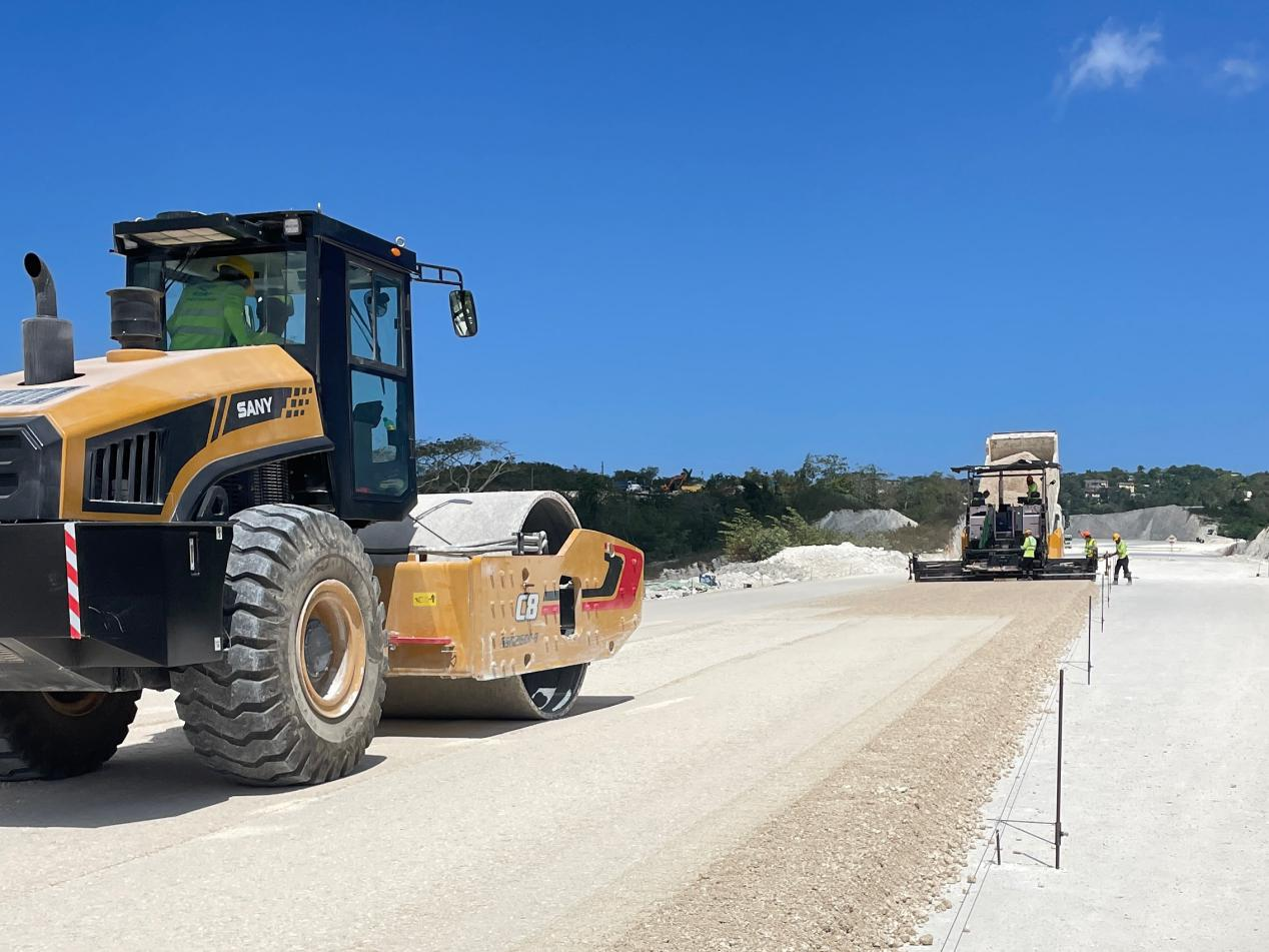 圖為中企承建的牙買(mǎi)加蒙特哥貝繞城路項(xiàng)目基層試驗(yàn)段正在進(jìn)行攤鋪和碾壓施工，相關(guān)施工工作已于日前順利完成。中國(guó)港灣美洲區(qū)域公司供圖