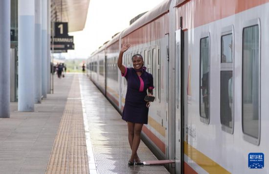 5月31日，在蒙內(nèi)鐵路內(nèi)羅畢站，一名乘務(wù)員在即將開往蒙巴薩的E2次列車旁等候乘客。新華社記者 李亞輝 攝